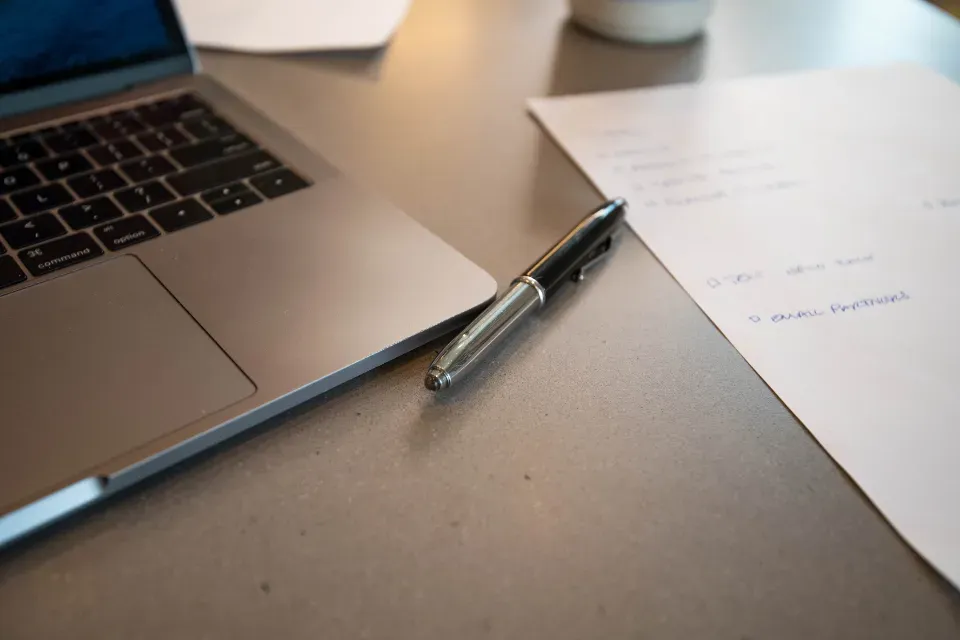Laptop with handwritten notes and a pen, planning an order