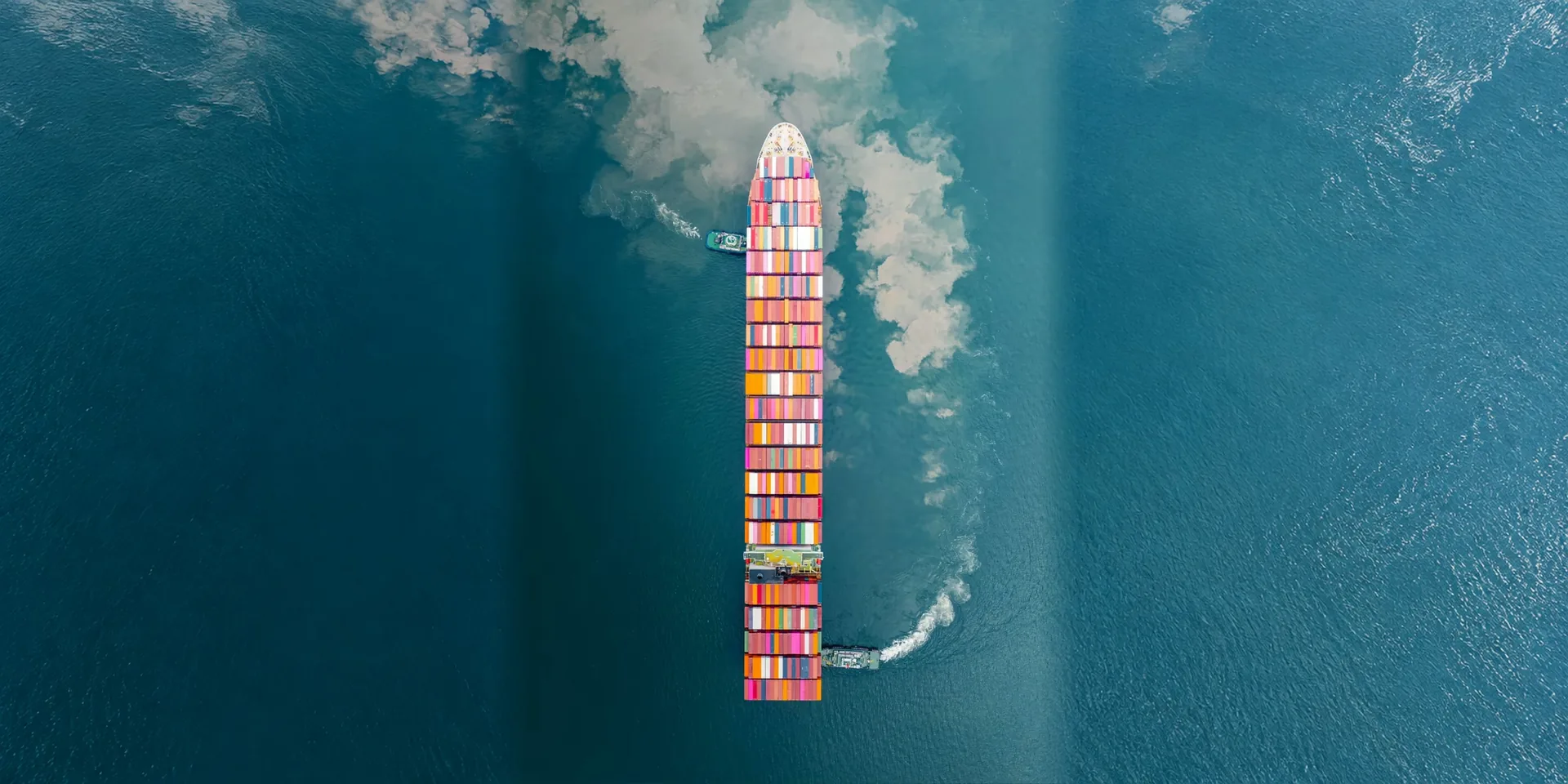 A container ship cutting a wake through deep blue water